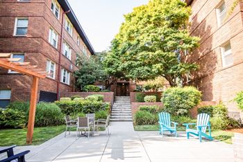 a patio with chairs and tables in front of a brick building